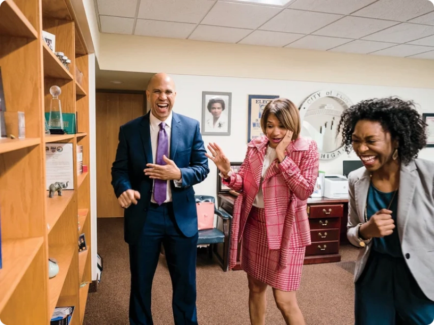 Senator Cory Booker laughing with two campaign leaders and advisors